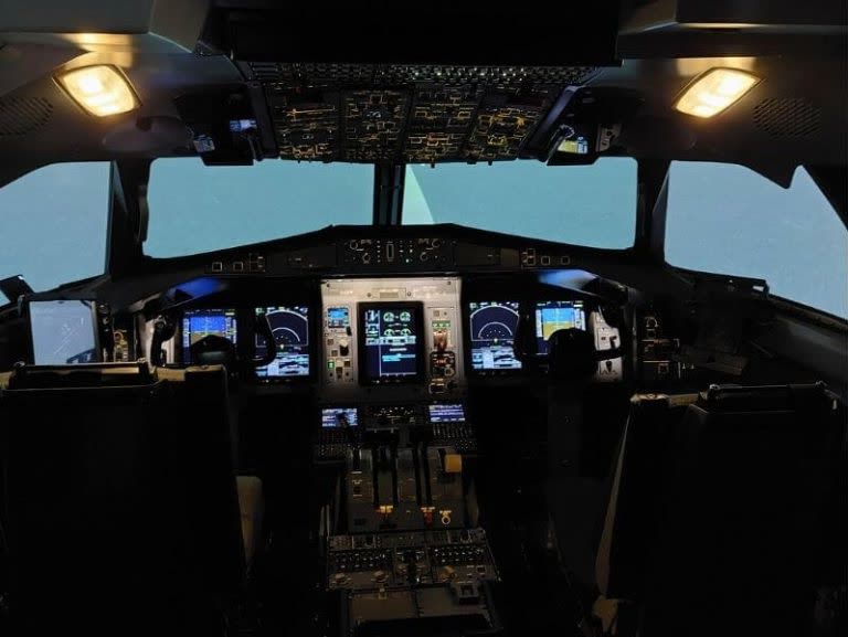 Flight simulator cockpit interior with full instrument panels and dual crew stations