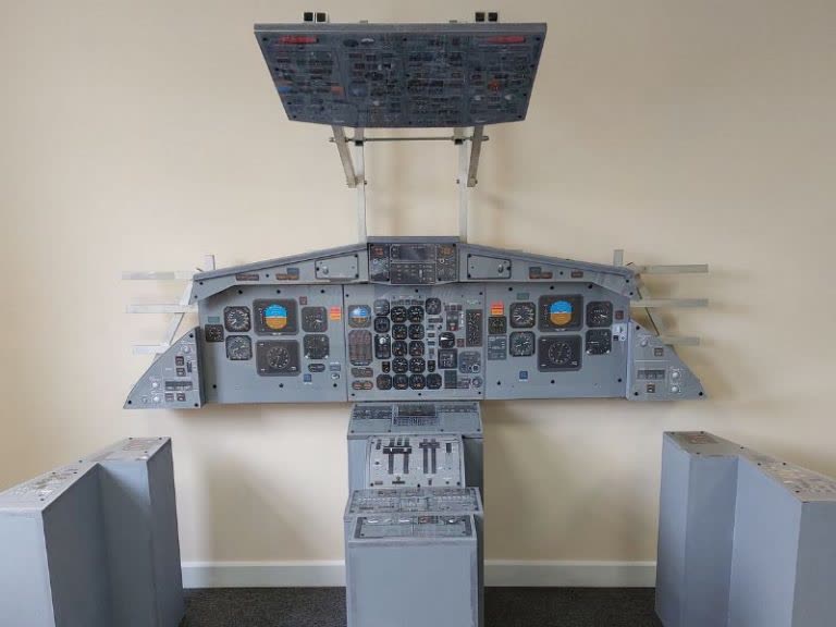 Vintage aircraft cockpit panel wall display with analog flight instruments and controls